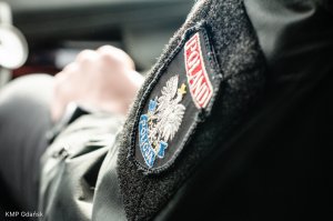Wnętrze radiowozu, naszywka na mundurze z napisem Poland, wizerunek orła, Policja