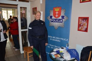Policjantka stoi przy banerze z logo Policji