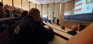 Zagraniczni studenci w auli wykładowej słuchają policjanta