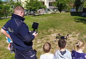 Policjant pokazuje grupie dzieci lot drona