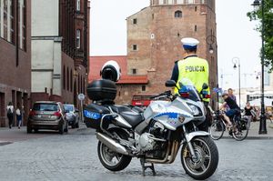 Policjant ruchu drogowego stoi przy policyjnym motocyklu.