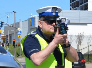 Policjant ruchu drogowego mierzy prędkość samochodów