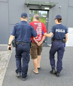 Policjanci wprowadzają zatrzymanego mężczyznę do komisariatu