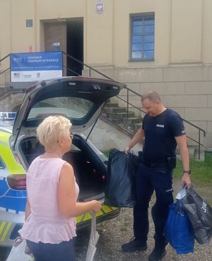 Policjant wyjmuje torby z ubraniami z radiowozu