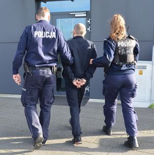 Policjanci prowadzą zatrzymanego mężczyznę