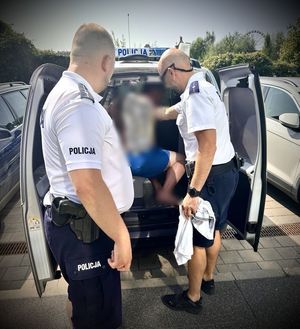 Policjanci umieszczają w radiowozie zatrzymanego