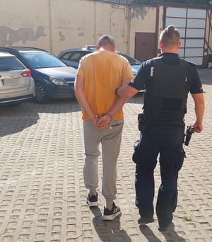 Policjant prowadzi zatrzymanego mężczyznę