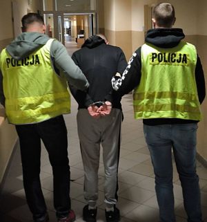 Policjanci prowadzą zatrzymanego mężczyznę