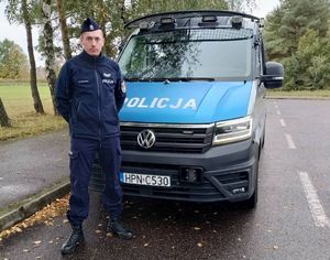 Policjant stoi przed radiowozem