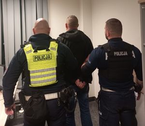 Policjanci stoją z zatrzymanym mężczyzną