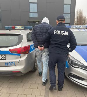 Policjanci prowadzą zatrzymanego mężczyznę