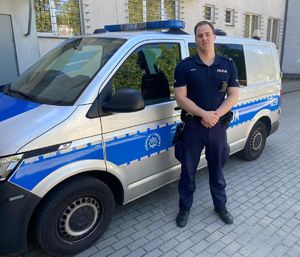 Policjant na tle radiowozu