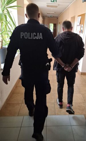 Policjant prowadzi zatrzymanego mężczyznę