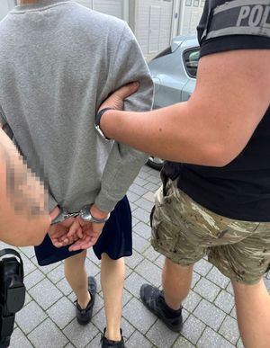 Policjanci prowadzą zatrzymanego mężczyznę