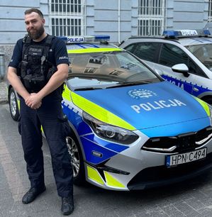 Policjant stoi przed radiowozem