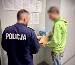 Policjant stoi przy zatrzymanym mężczyźnie