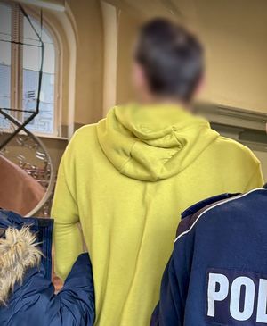 Policjanci prowadzą zatrzymanego mężczyznę