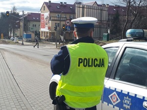 Policjant stoi obok radiowozu
