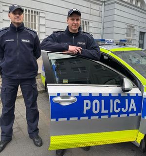 Dwaj policjanci stoją przy radiwozie