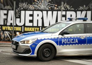 Policyjny radiowóz na tle baneru z fajerwerkami