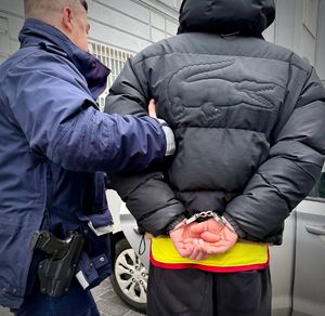 Policjant prowadzi zatrzymanego mężczyznę
