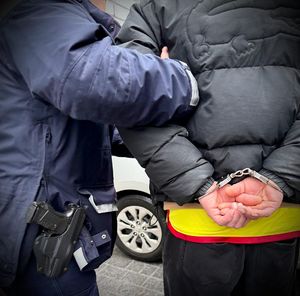 Policjant prowadzi zatrzymanego mężczyznę